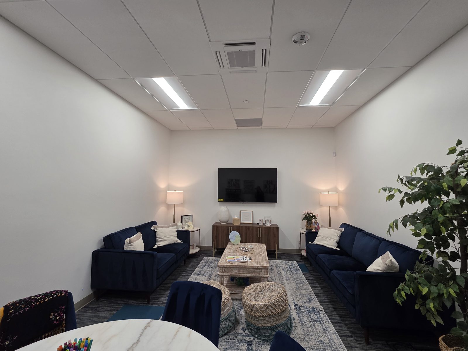 A family and couples room with navy velvet sofas, calligraphy art, and natural light