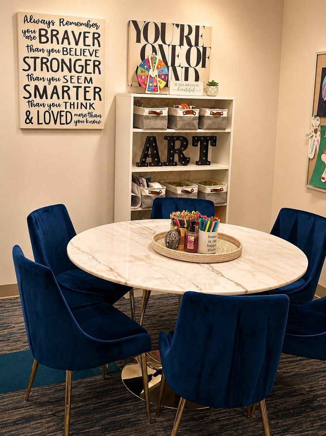 A youth art therapy room with a round marble table, art supplies, and children’s artwork